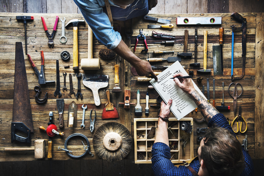 Woodworkers discussing a project over a table of tools