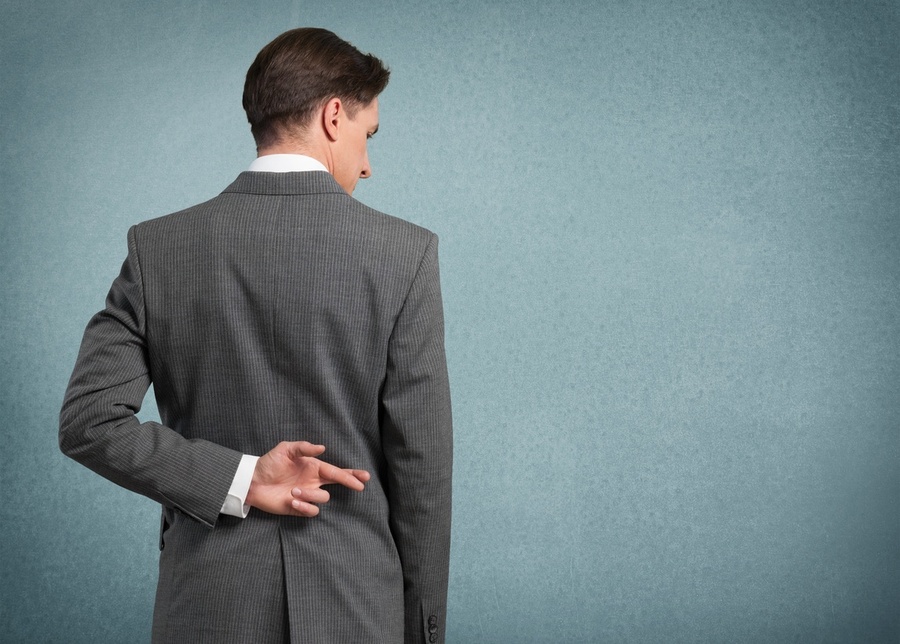 Man in suit with fingers crossed behind his back