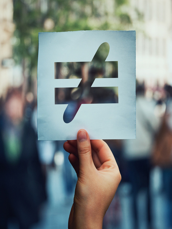 unequal sign held up in front of people