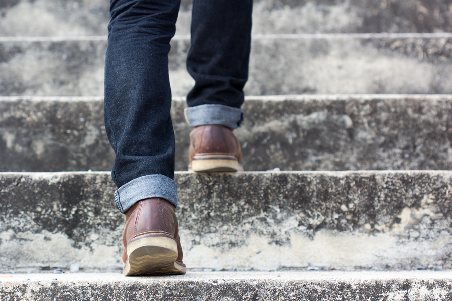 Feet in sturdy shoes shown walking up steps from behind