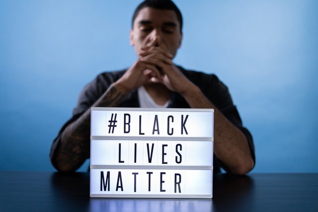 Black man sitting with Black Lives Matter sign
